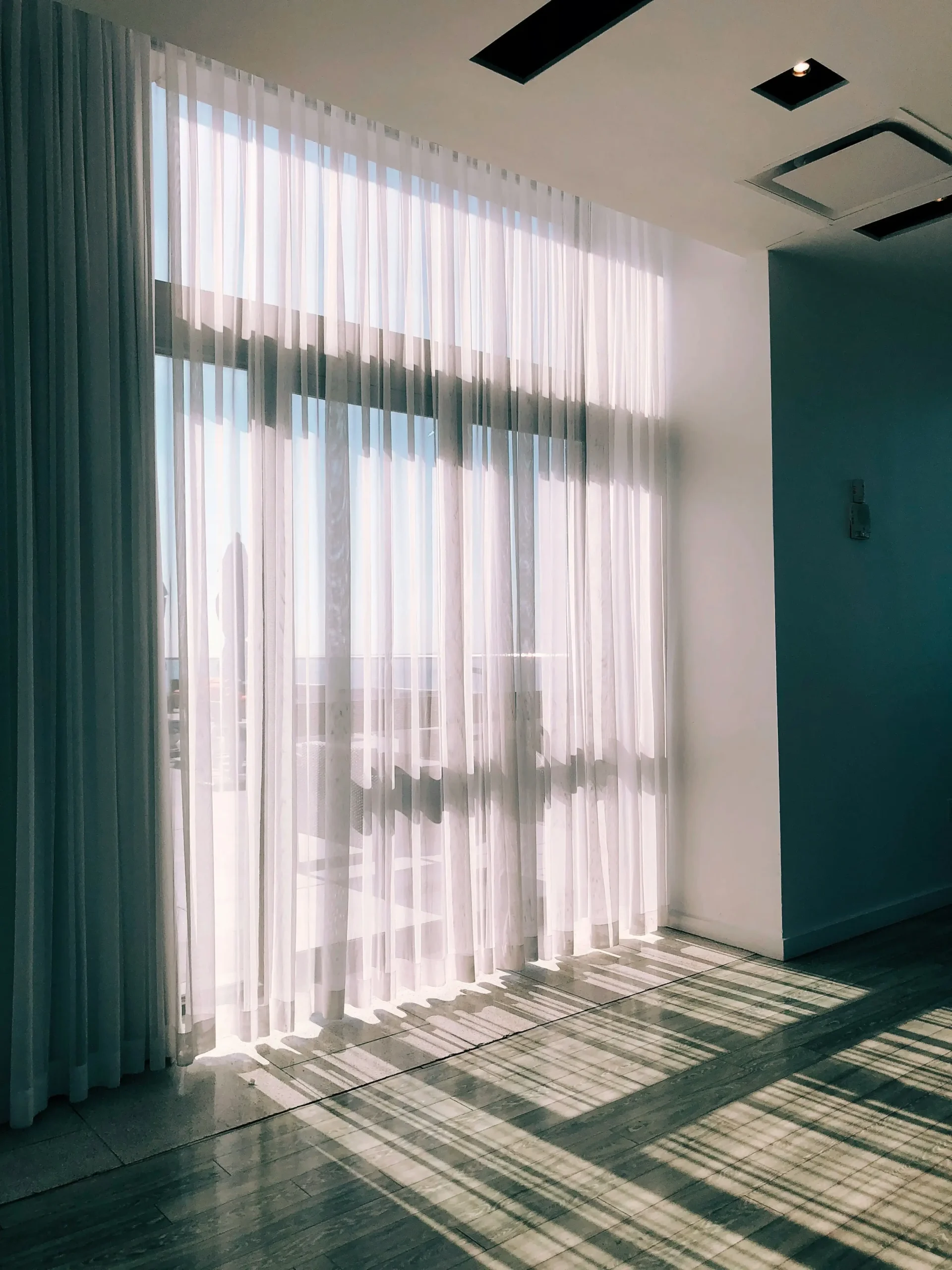 Technician carefully rehanging freshly cleaned drapes in a Vancouver home.