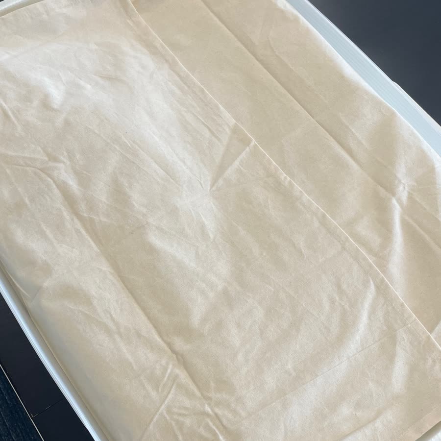 Unbleached muslin layer covering the gown inside the box