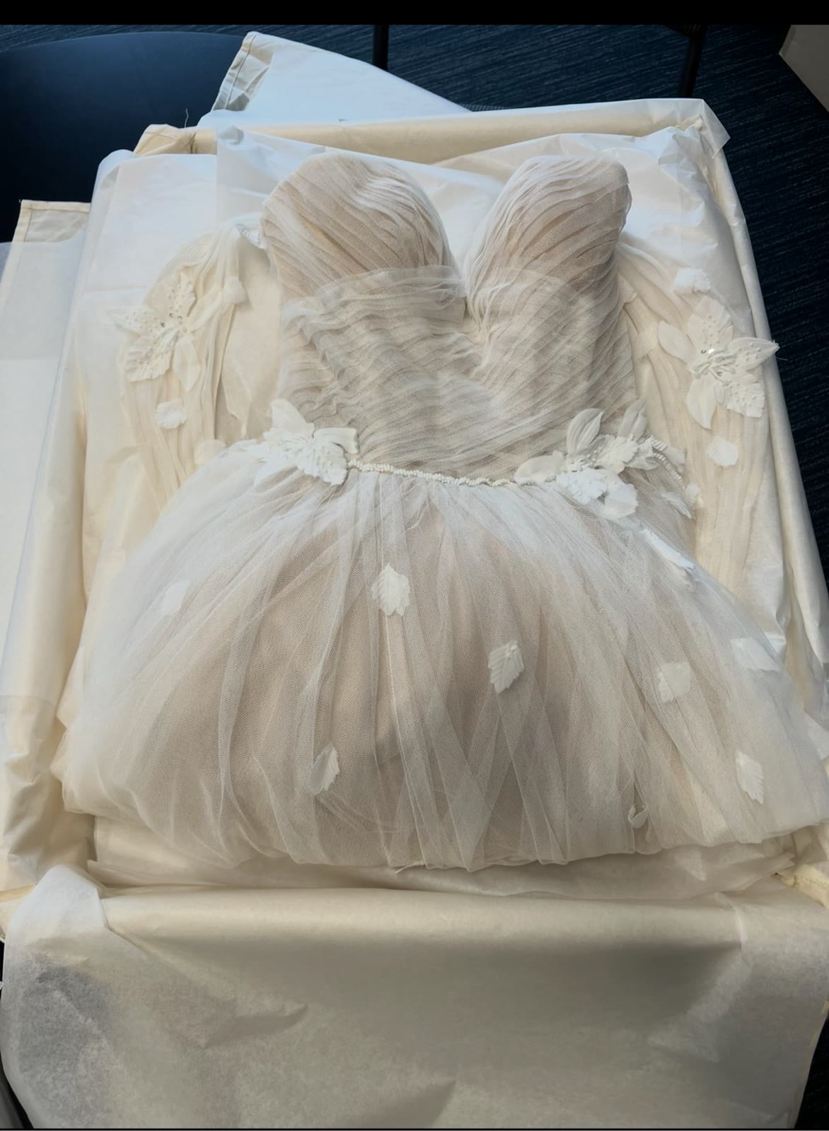 Tulle wedding gown with hand-sewn appliqués nestled in tissue inside a preservation box